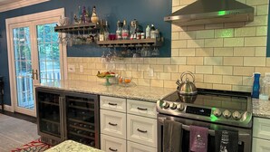 Una cocina con horno empotrado, campana extractora de acero inoxidable y una vinoteca sobre la encimera.
