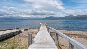 Une jetée en bois qui mène à un lac paisible, avec des montagnes en arrière-plan.