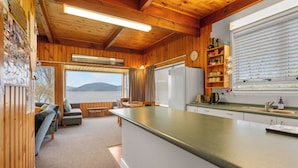 L’intérieur d’une cabane comprenant une cuisine, un coin repas et une vue sur un lac.