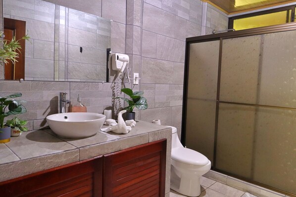 A bathroom with a large sink, a toilet, and a shower area.