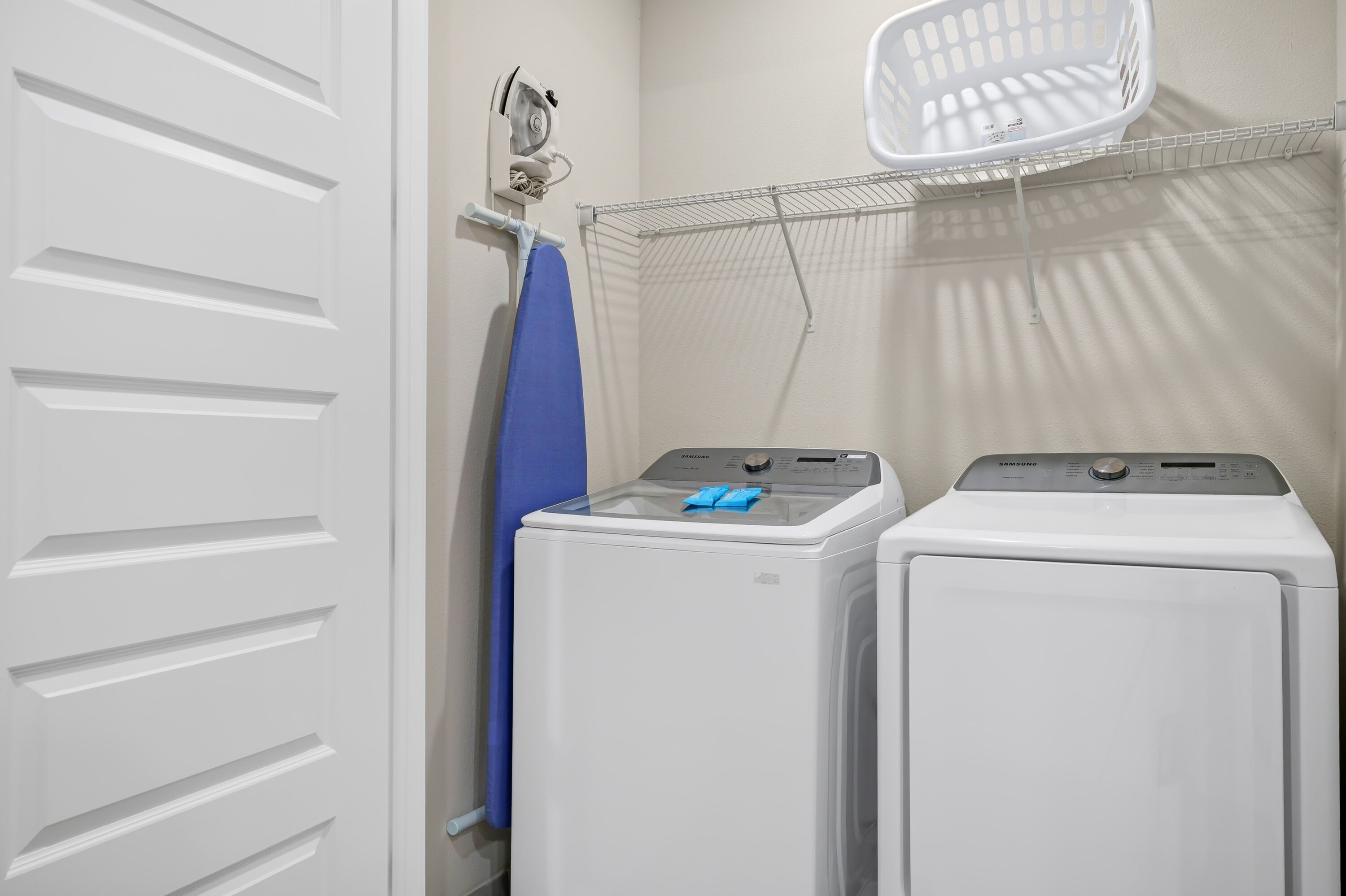 A laundry area with two white washing machines and a drying rack.