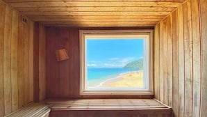 Eine Holzjagdhaushütte mit einer Bank und einem Fenster mit Blick auf einen Strand.