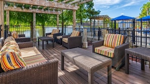 An outdoor deck with wicker furniture, a pergola, and a view of a lake. - Enjoy all the Theme Parks and what Orlando has to offer at Terra Verde Resort! (Kissimmee)