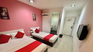 Ein Hotelzimmer mit zwei Betten, roter und weißer Bettwäsche, einem Fernseher und einem Duschbereich.