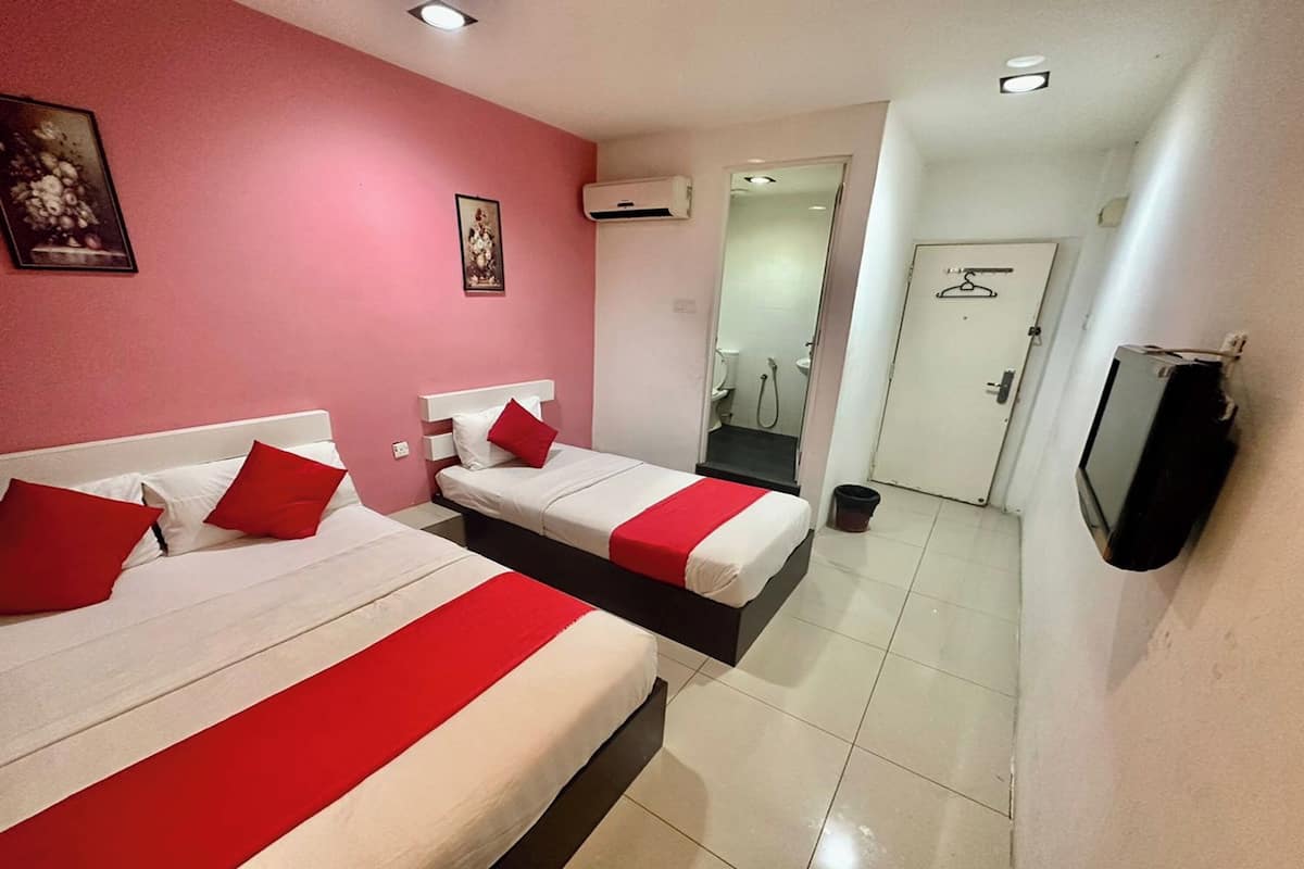 Hotelkamer met twee bedden, rood-witte beddengoed, een televisie en een douche.