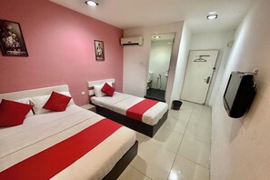 Une chambre d’hôtel avec deux lits, une télévision, un appareil de climatisation et une salle de bain visible à travers une porte ouverte.