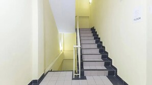 Una escalera con escalones alternados en blanco y negro, un pasamanos y un cartel que indica el tercer piso.