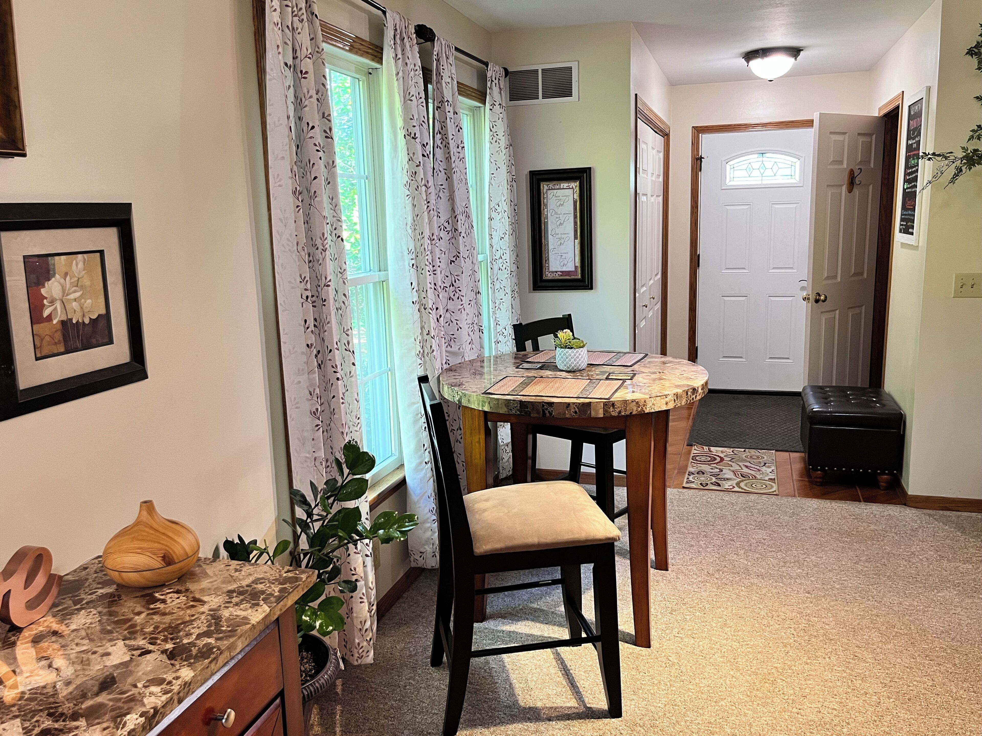 A dining area with a round table, chairs, a vase, and a potted plant.