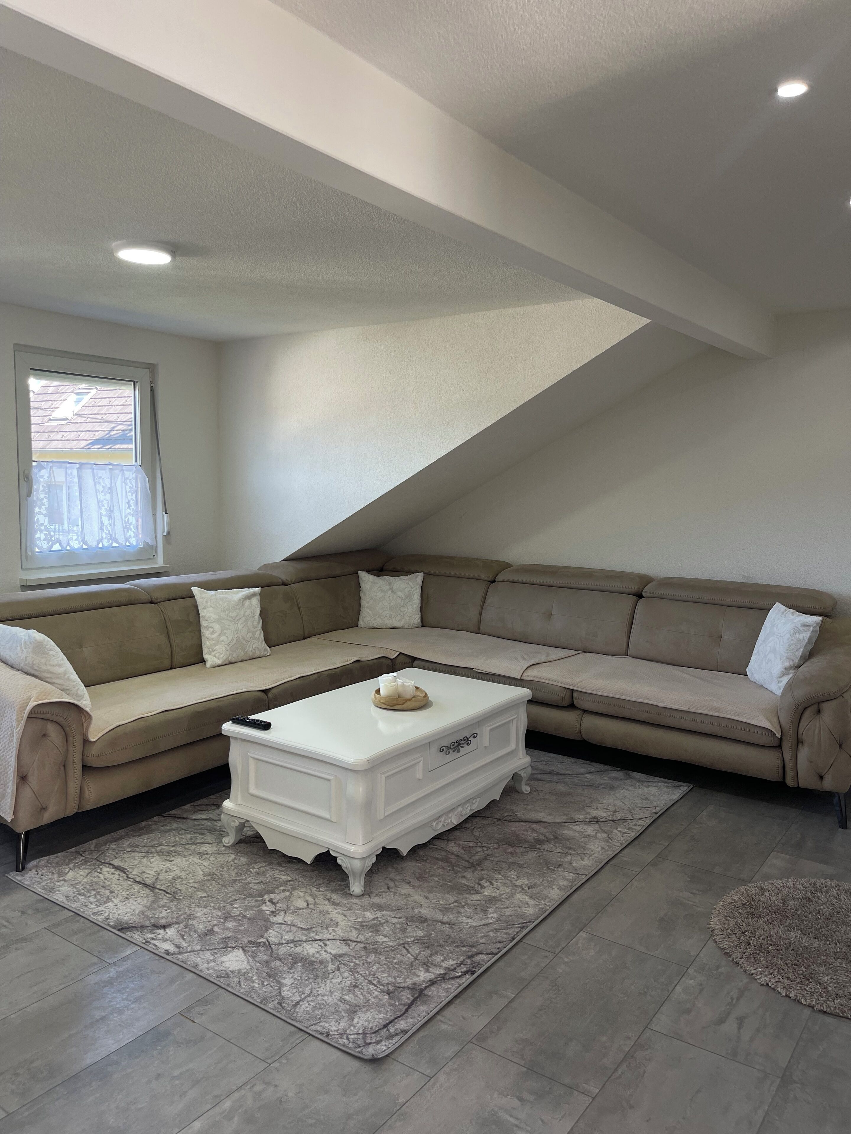 A living room with a sectional sofa, a white coffee table, and a patterned rug.