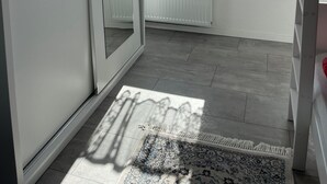 Ein Zimmer mit einer Schiebetür, einem Heizkörper, einem Fenster mit gemustertem Vorhang und einem Teppich mit Muster.