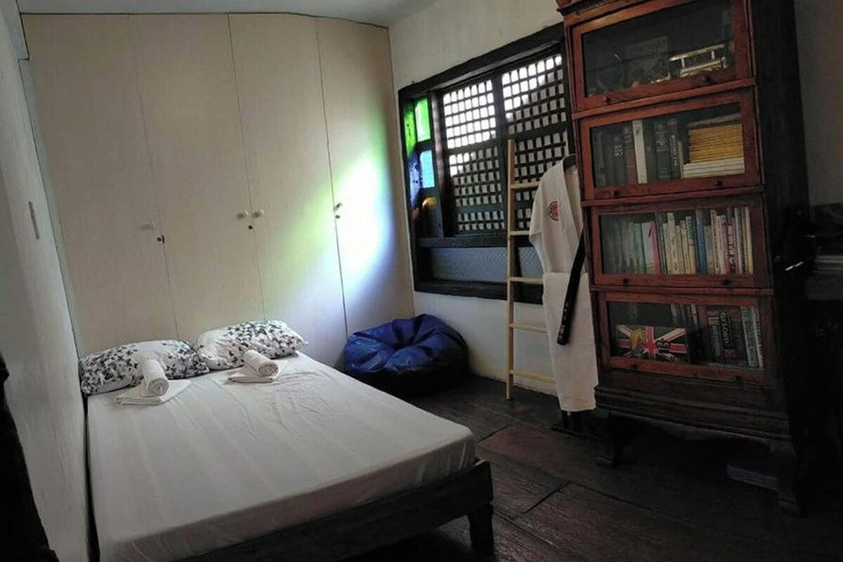 Un dormitorio con cama, armario, ventana con vistas y estantería.