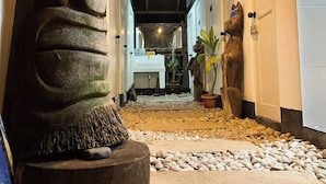 A hallway with a large stone sculpture, a potted plant, and a small garden area with pebbles. - Surfer's Villa La Union By Zuzu (San Juan)