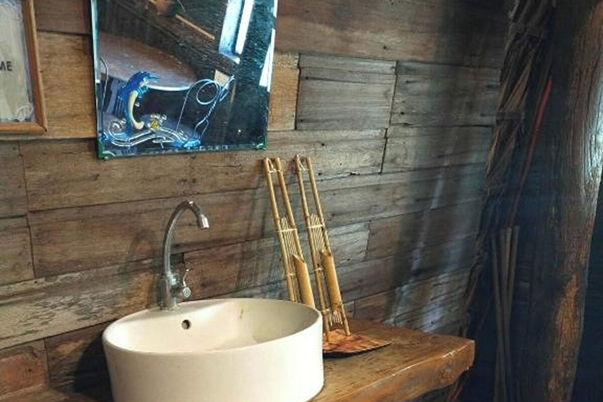 Un baño rústico con lavamanos de madera y un grifo antiguo.