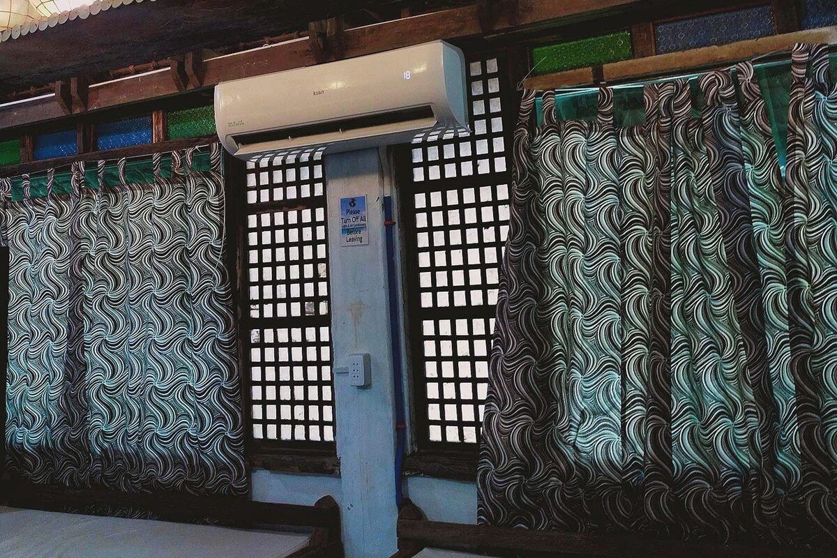 Una habitación japonesa tradicional con esteras de tatami, paneles shoji y faroles de papel colgantes.