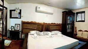 A bedroom with a wooden bed, a nightstand, a dresser, and a window with bars. - Surfer's Villa La Union By Zuzu (San Juan)