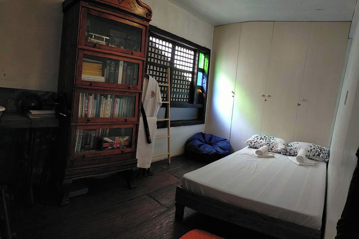 Un dormitorio con cama, armario, estantería y ventana con persianas.
