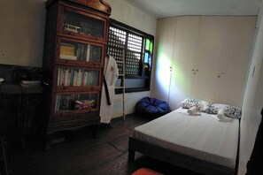 Un dormitorio con cama, armario, estantería y ventana con persianas.