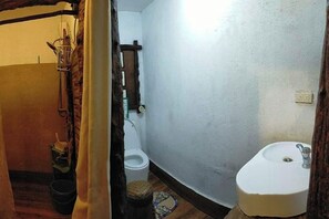 Un baño estrecho con inodoro, lavamanos y una alfombra pequeña en el suelo.