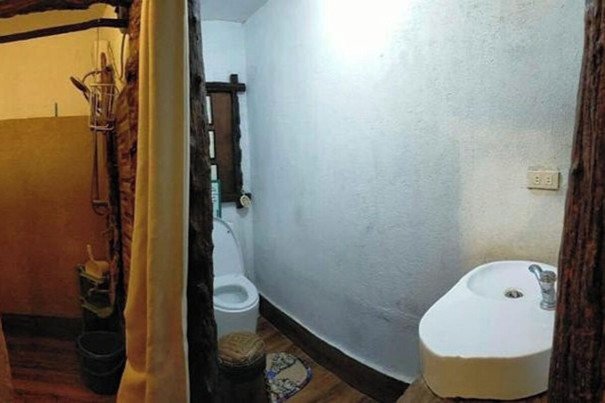 Un baño pequeño y estrecho con un lavamanos blanco, un inodoro y una zona de ducha.