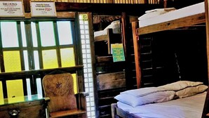 A room with bunk beds, a chair, and a window with a sign. - Surfer's Villa La Union By Zuzu (San Juan)