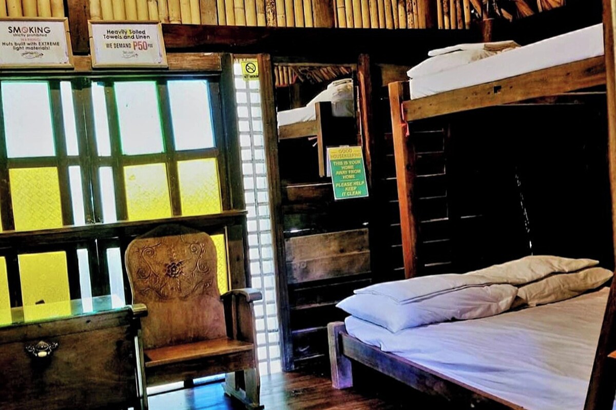 Una habitación con literas, una silla y un ventanal con un letrero.