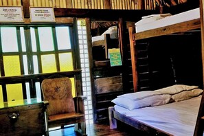 Una habitación con literas, una silla y un ventanal con un letrero.