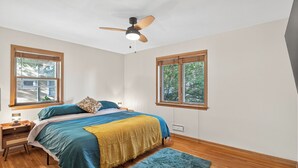 A bedroom with a bed, nightstand, lamp, and a ceiling fan.