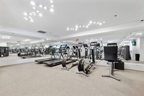 Et moderne fitnesscenter med løbebånd, crosstrainere og styrkeudstyr.