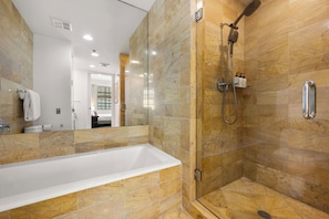 Un bagno moderno con vasca, doccia e piastrelle in marmo.