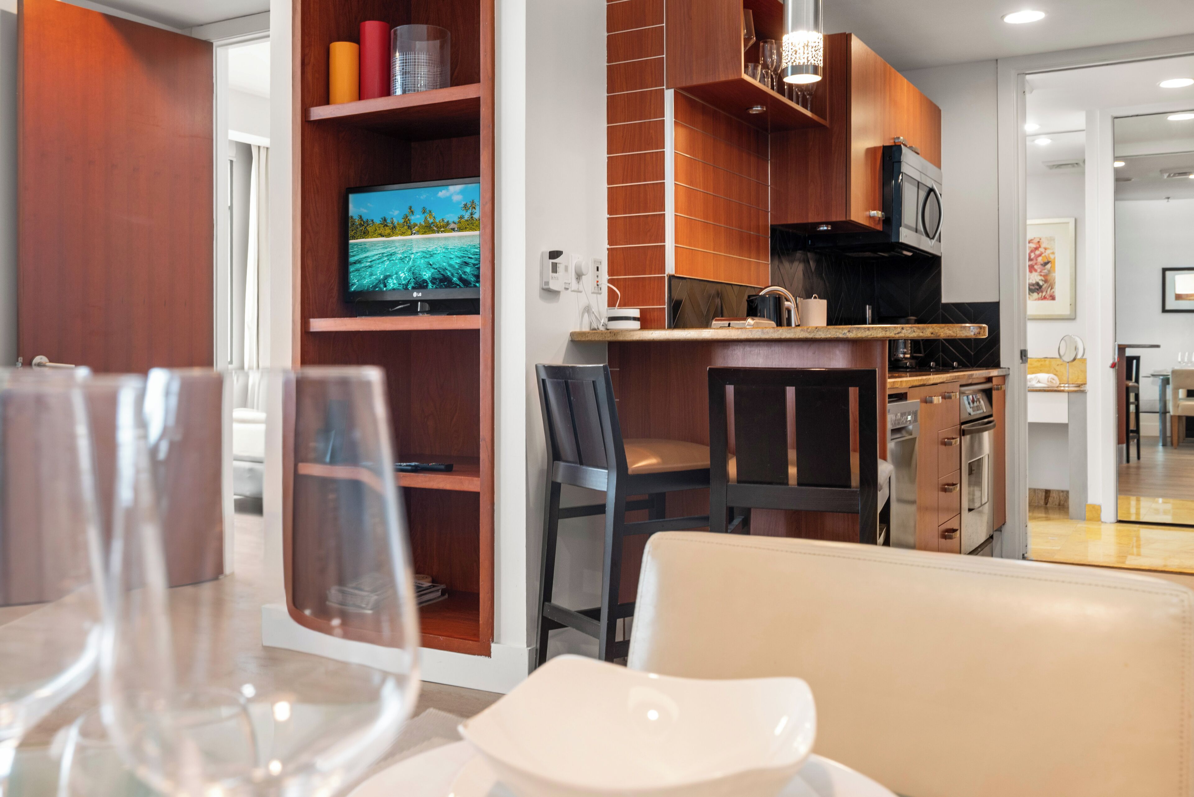 A modern kitchen with wooden cabinets, a built-in oven, and a television.