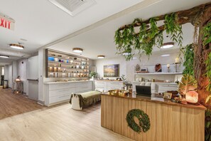 En moderne hotellobby med en receptionsdisk, trægulv og en stor reol fyldt med dekorative genstande.