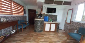 Un salon avec une cheminée en pierre, un téléviseur fixé au mur et une table à manger en bois.