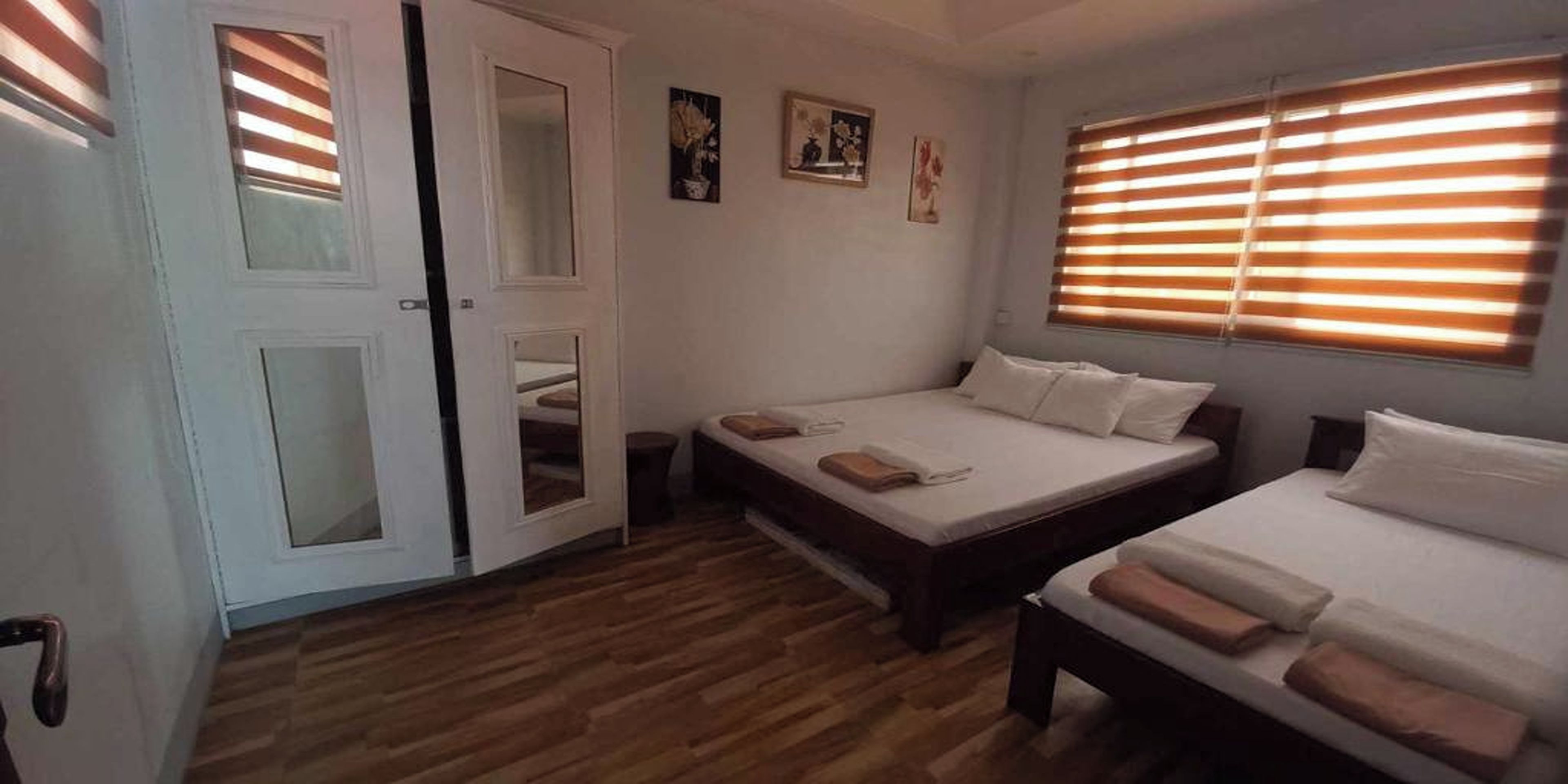 Camera da letto con due letti, pavimento in legno e una porta con pannelli di vetro.