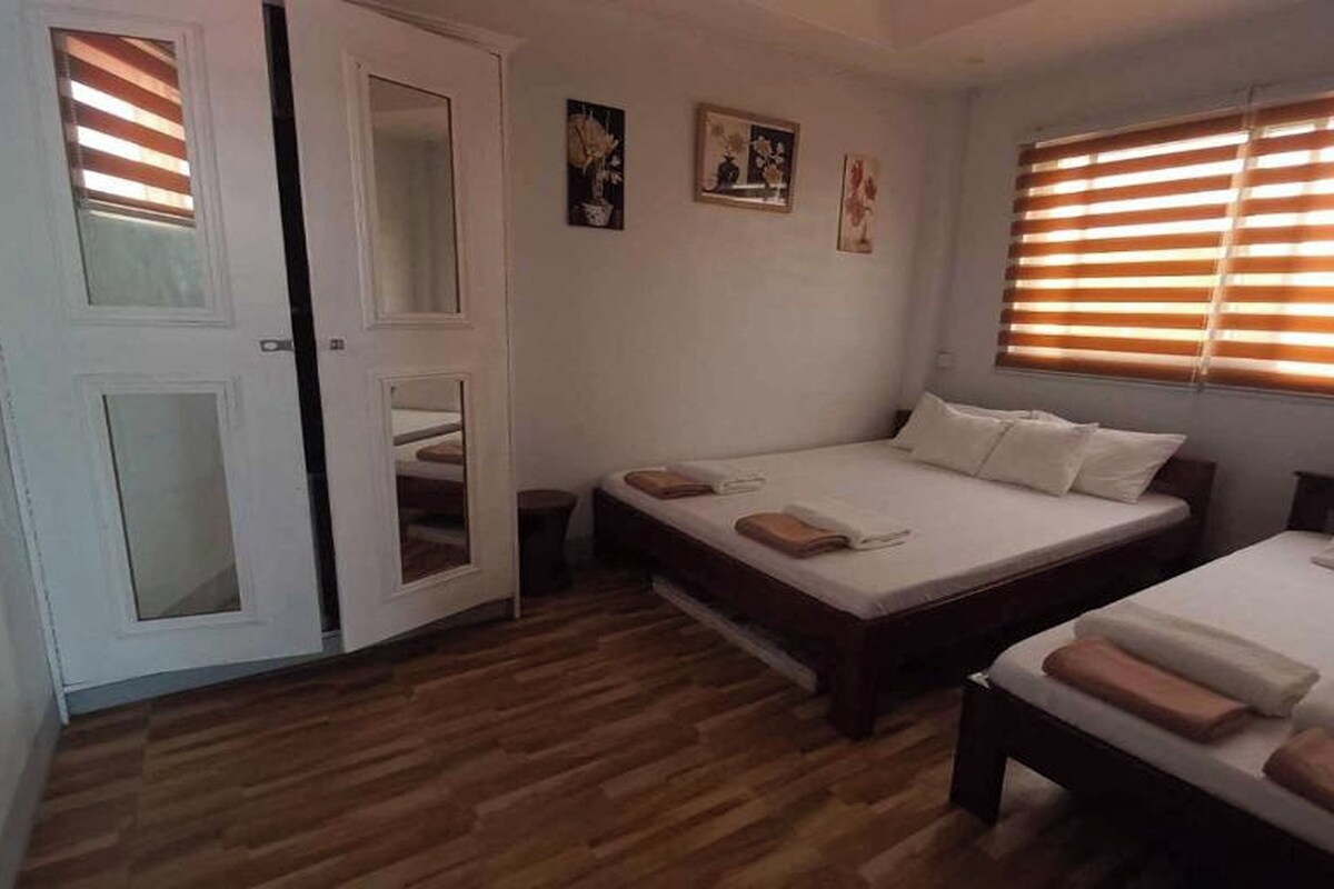 Ein Schlafzimmer mit zwei Betten, Holzboden und einer Tür mit Glasfeldern.