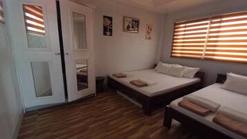 Camera da letto con due letti, pavimento in legno e una porta con pannelli di vetro.
