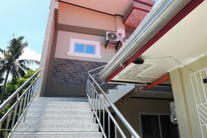Un escalier menant à l’entrée d’un immeuble, avec une fenêtre et un appareil de climatisation.