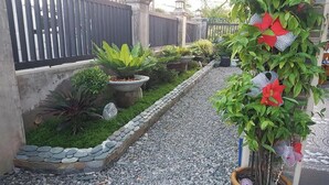 Ein Gartenweg mit Kübelpflanzen und einem Zierzaun.