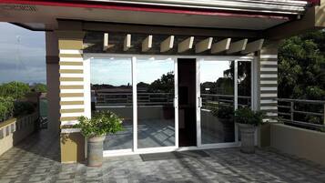 A covered outdoor area with a glass door entrance, potted plants, and a tiled floor.