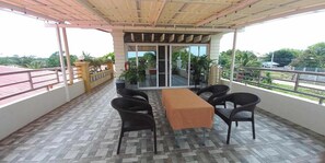 Un balcon abrité, doté d’une table et de chaises, offrant une vue sur la verdure environnante et dont le sol est carrelé.