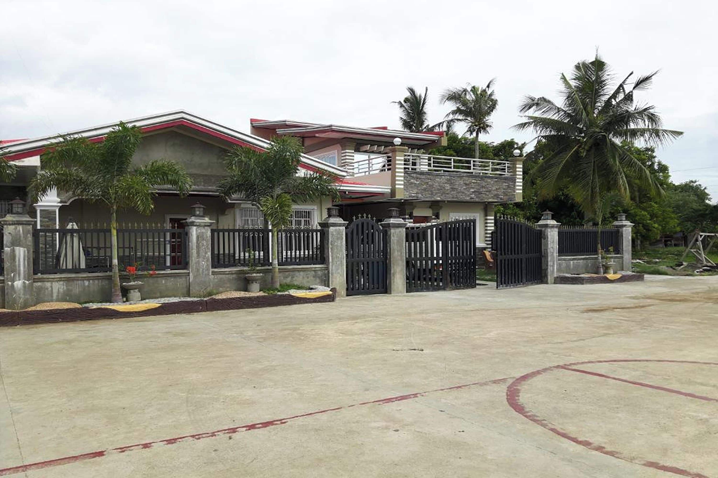 A two-story house with a gated entrance, a balcony, and a concrete driveway.