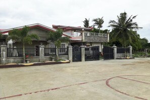 A two-story house with a gated entrance, a balcony, and a concrete driveway. - Fnt Transient House Near Hundred Islands By Zuzu (Alaminos)