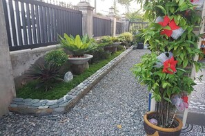 Un chemin de jardin bordé de plantes en pot et agrémenté d’une clôture décorative.