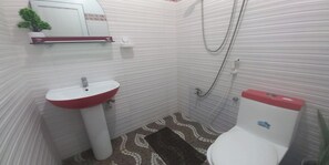 Een badkamer met een witte wastafel, een toilet en een douche.