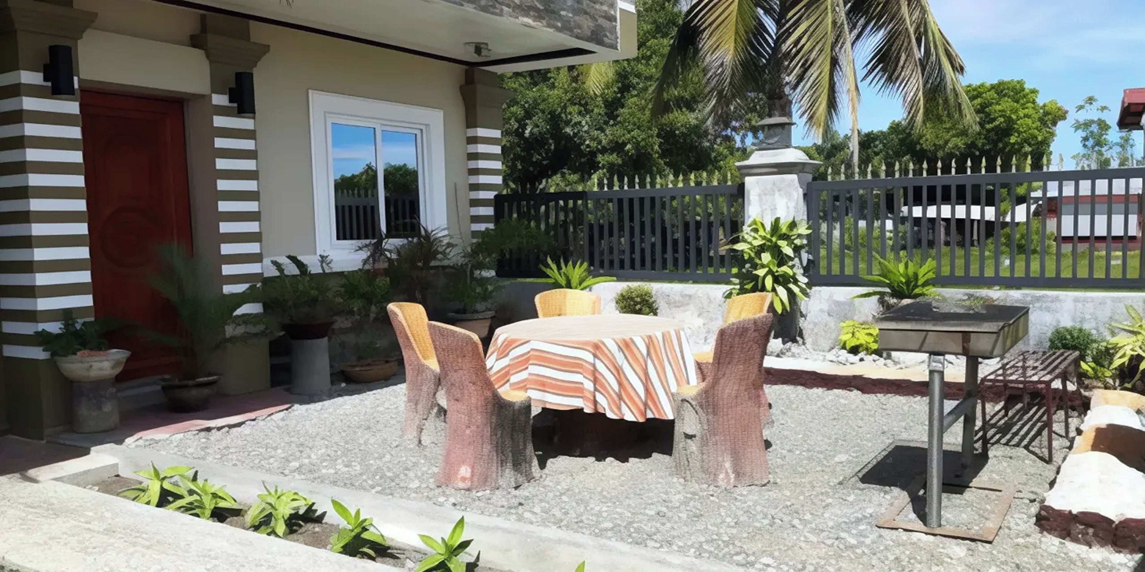 A patio with a table and chairs, surrounded by potted plants and a gravel area.