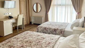A hotel room with two beds, a desk, a chair, a television, and a mirror.
