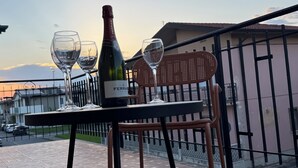 Een tafel met een fles wijn en twee glazen op een balkon.