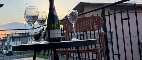 Una mesa con una botella de vino y dos copas en un balcón.