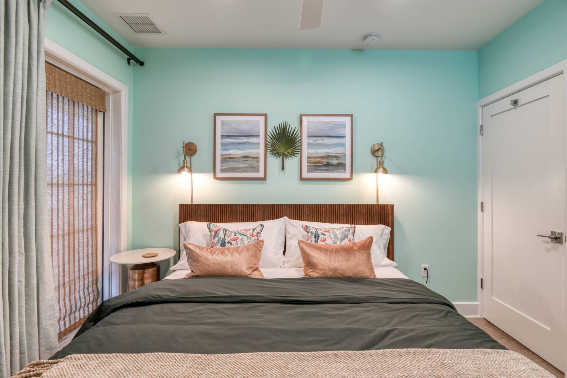 A bedroom with a bed, two wall-mounted lamps, and two framed pictures.