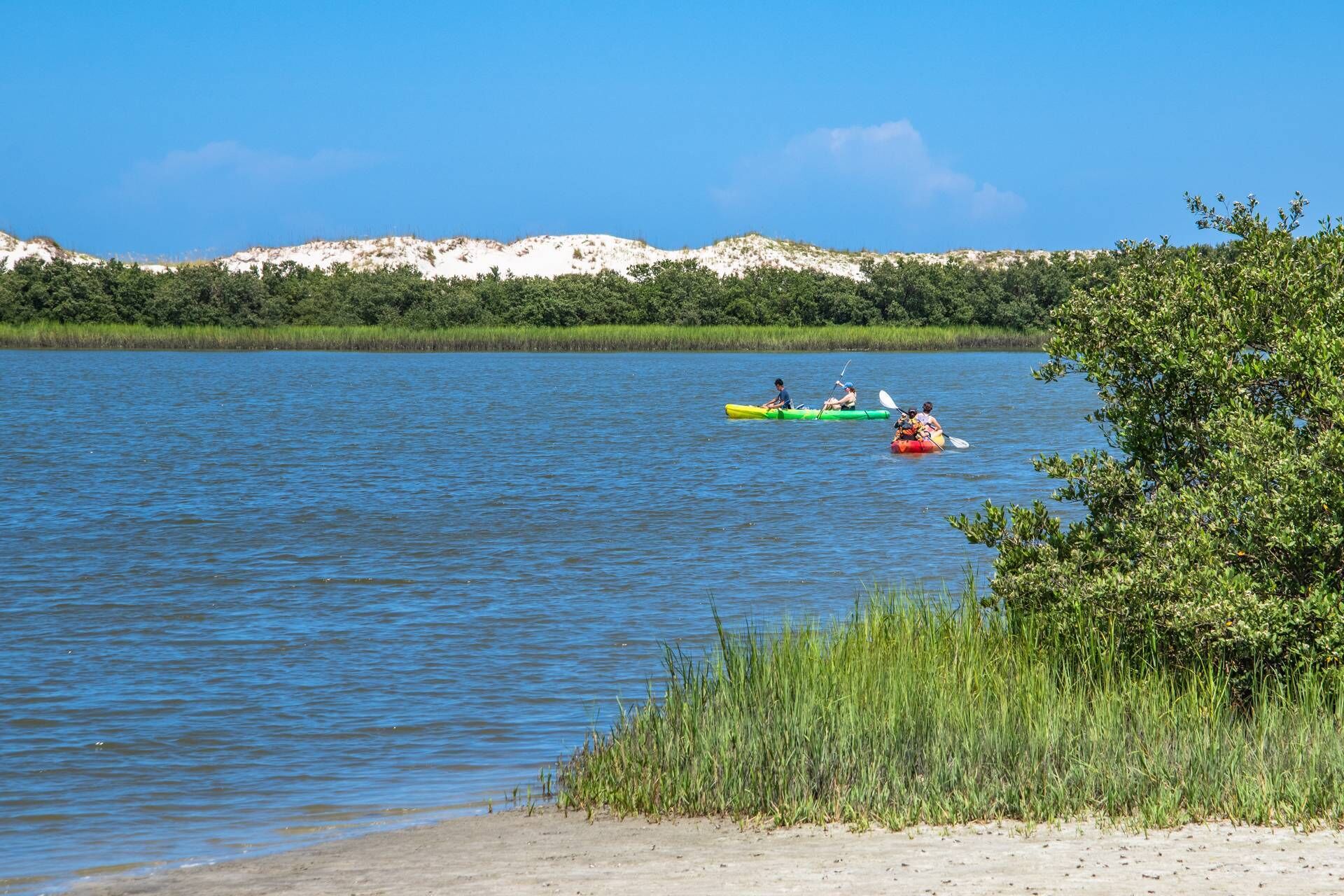 A calm lake with kayaks and a sandy beach.