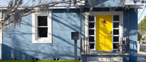 A two-story house with a bright yellow door and a small porch.